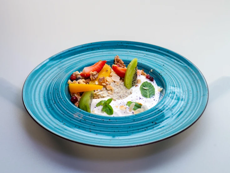 a blue bowl with fruit and vegetables on a table