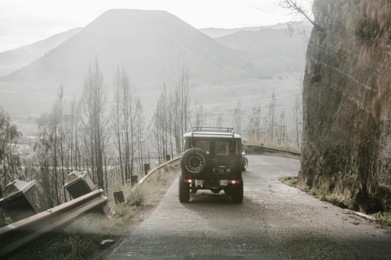 a car drives down a mountain road with some hills in the background