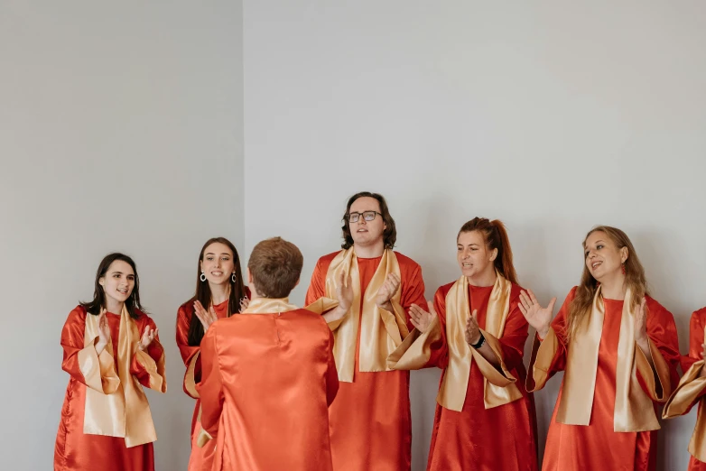 five people in long red and gold dresses standing together