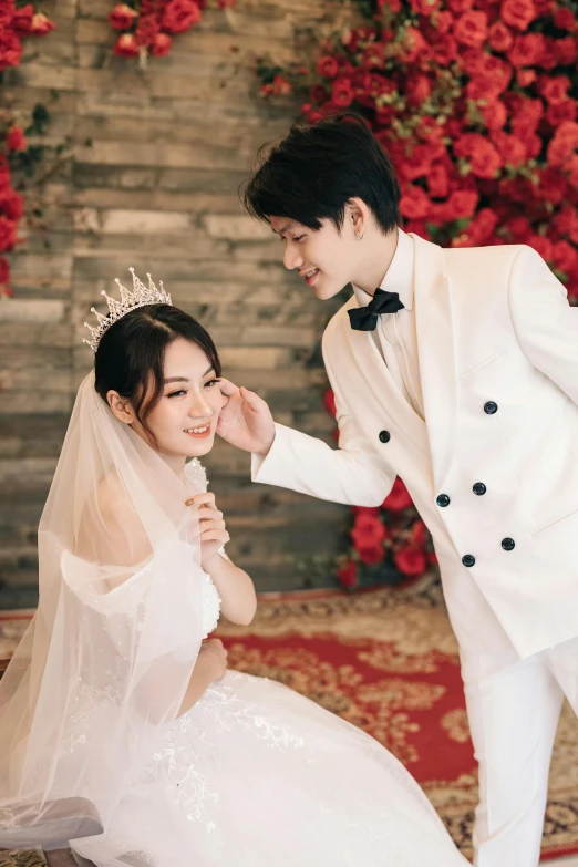 the man in a tuxedo is kneeling near the woman in a wedding dress