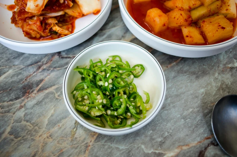 three bowls with stew and some green onions and vegetables