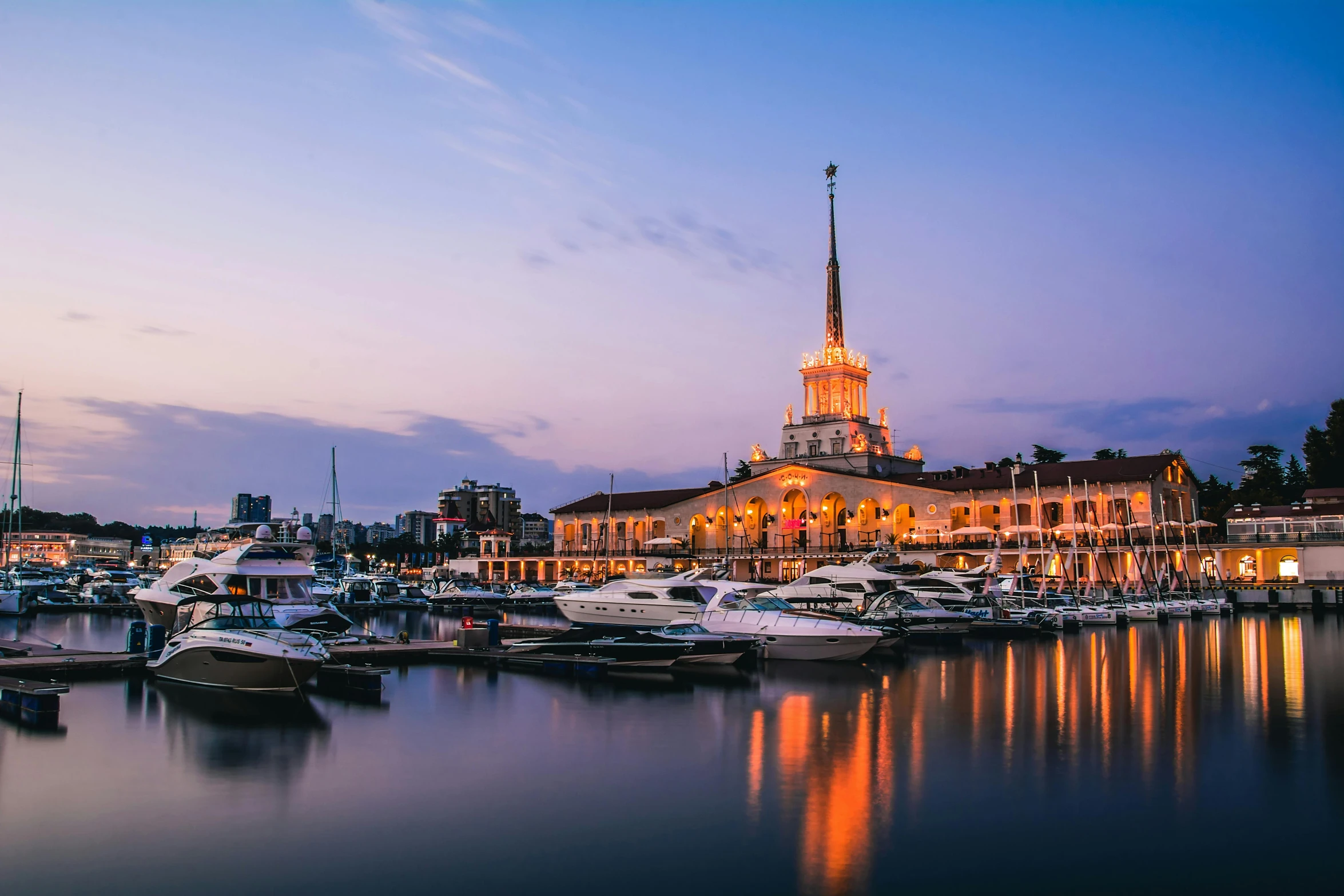 this is a town and sea with boats at sunset