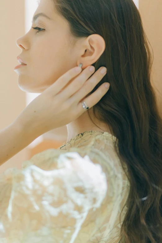 a woman in a dress adjusting the ear ring on her ears