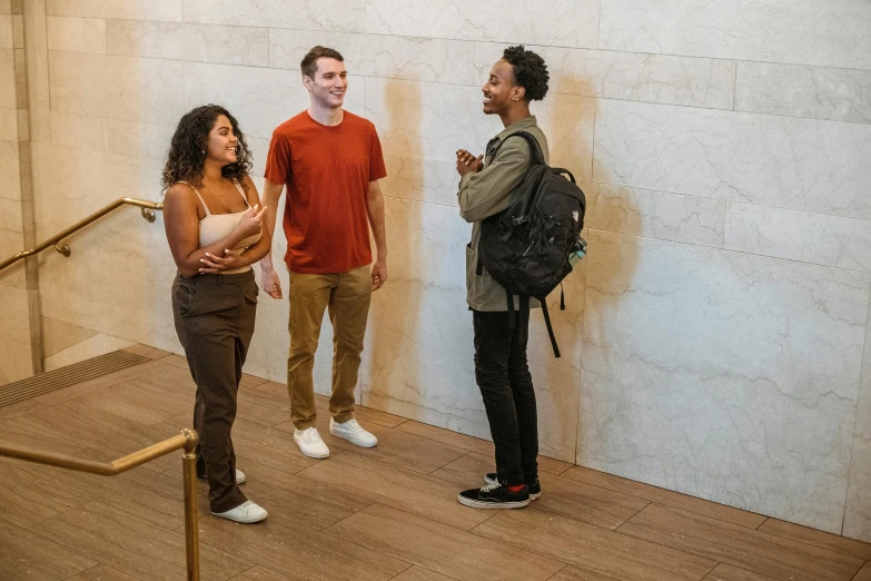 three people talk in front of the wall