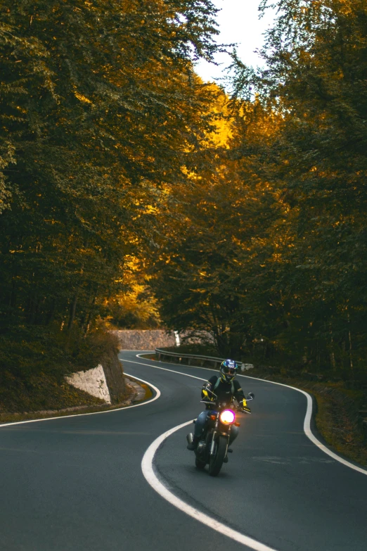 a man riding on the back of a motorcycle down a curvy road