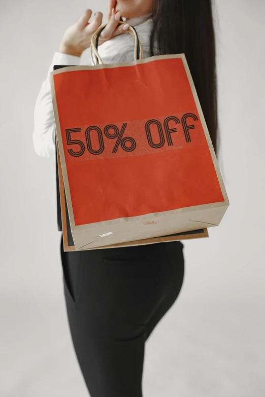 a woman carrying a brown bag with a sale sign on it