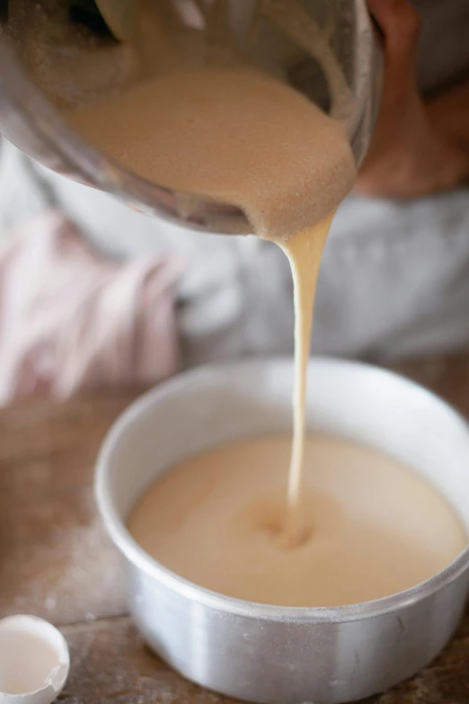 a person pouring some liquid over an empty bowl