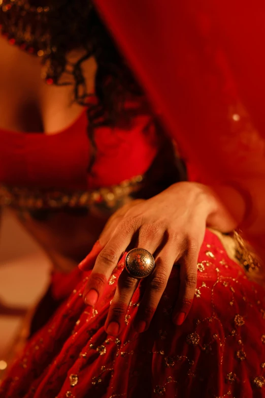 a woman in a red dress and gold jewelry is wearing a ring