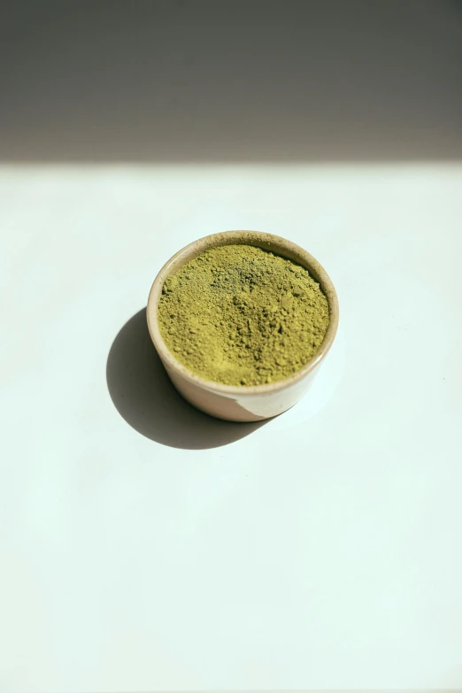 a bowl of green tea powder sits on a table