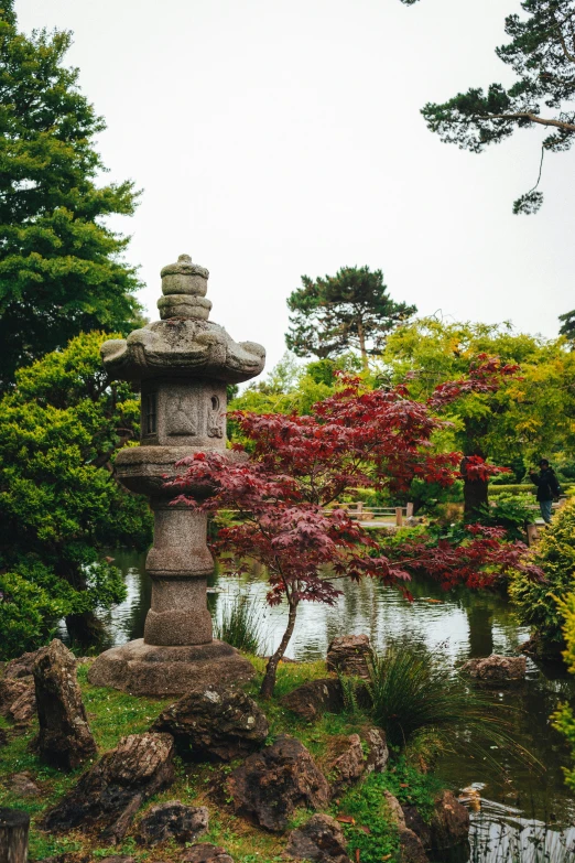 a park with a statue, flowers and trees