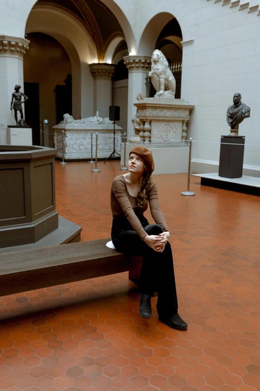 a woman sitting in front of a bronze sculpture