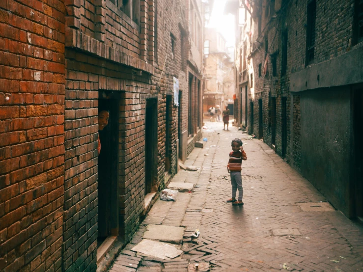 a little boy standing on the street and looking at soing in the distance