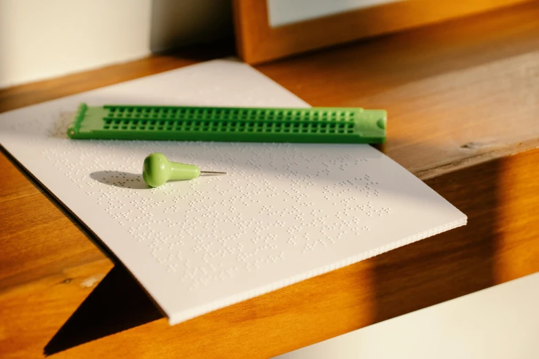 a green marker next to a white paper on a wooden table