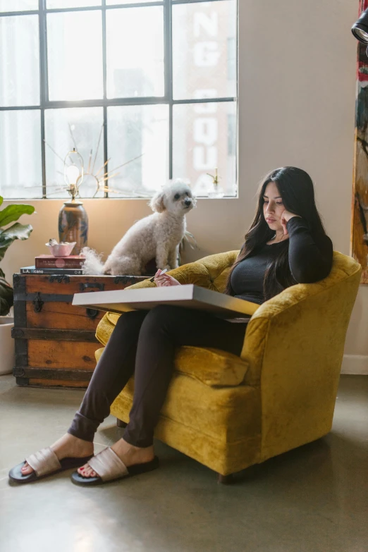 a beautiful young lady sitting in a chair near a dog