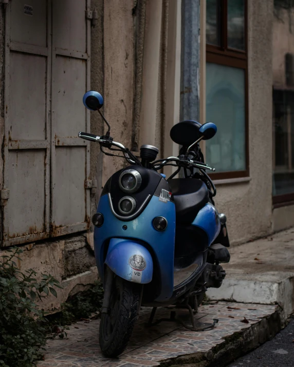 a blue motorcycle sits next to a building