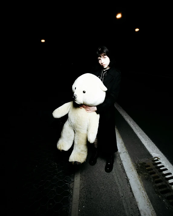 a person holding a large white teddy bear in the dark