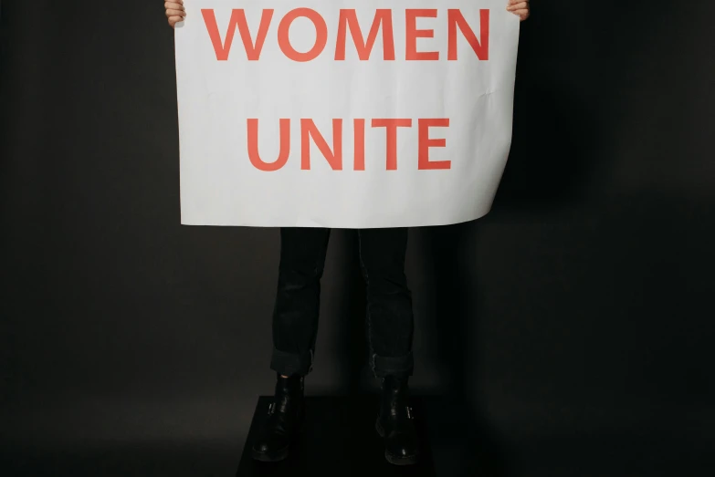 a woman holding a sign reading women united