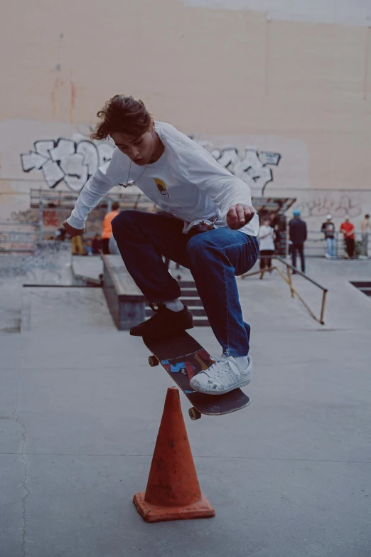 a boy riding a skateboard on top of an orange cone