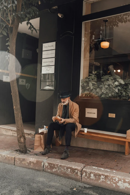 a man sits outside a store, using his phone