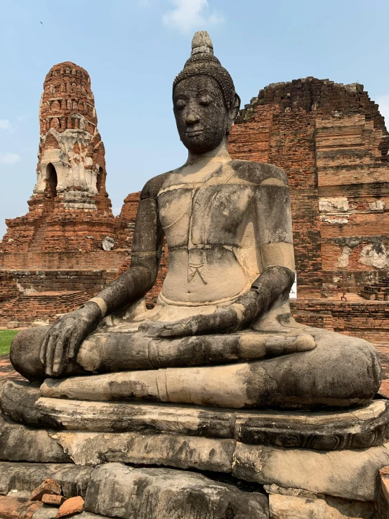 a small stone buddha statue in front of two small pagodas