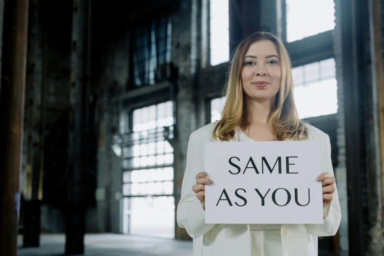 a woman holds up a sign with the words same as you