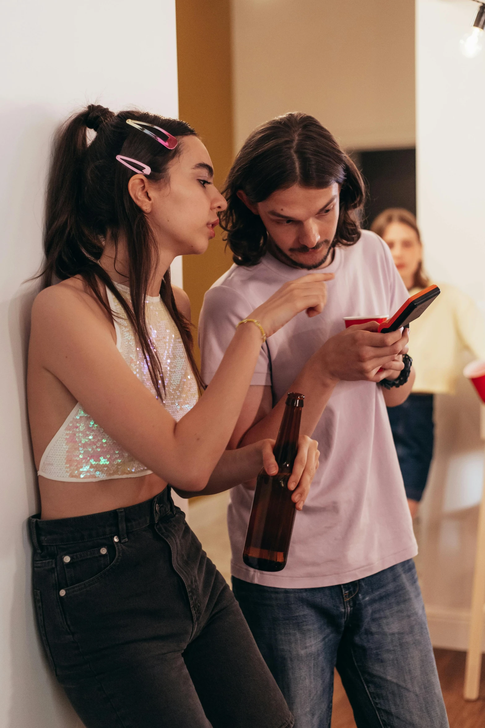 the couple are leaning against the wall and looking at their phones