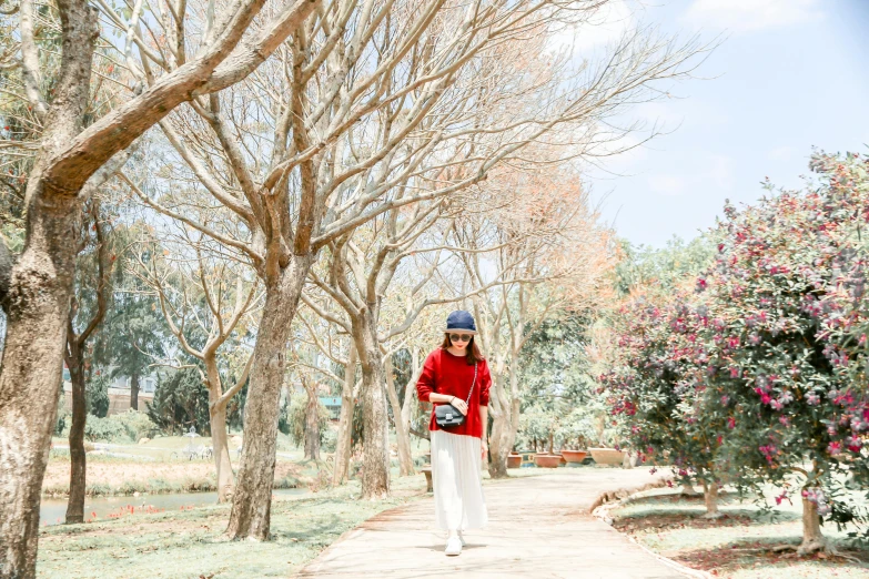 a woman walks through the park carrying an item