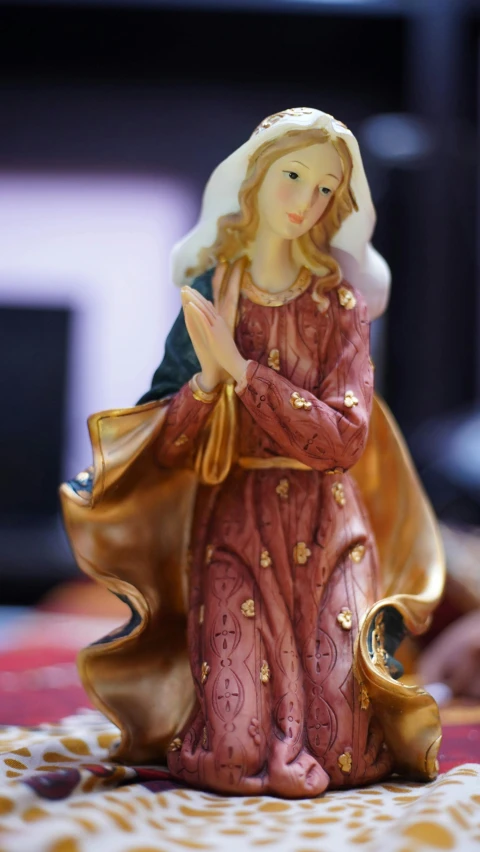 a little figurine is on a table with a red and gold cloth