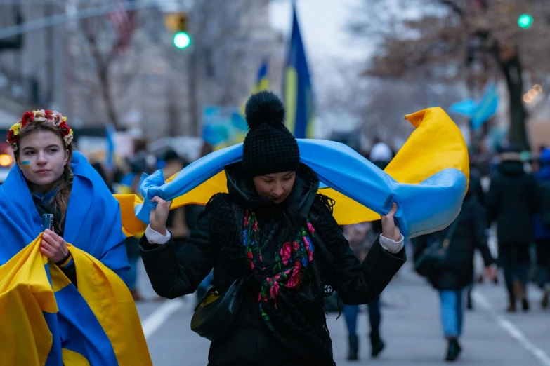 two women walking down the street carrying long blankets