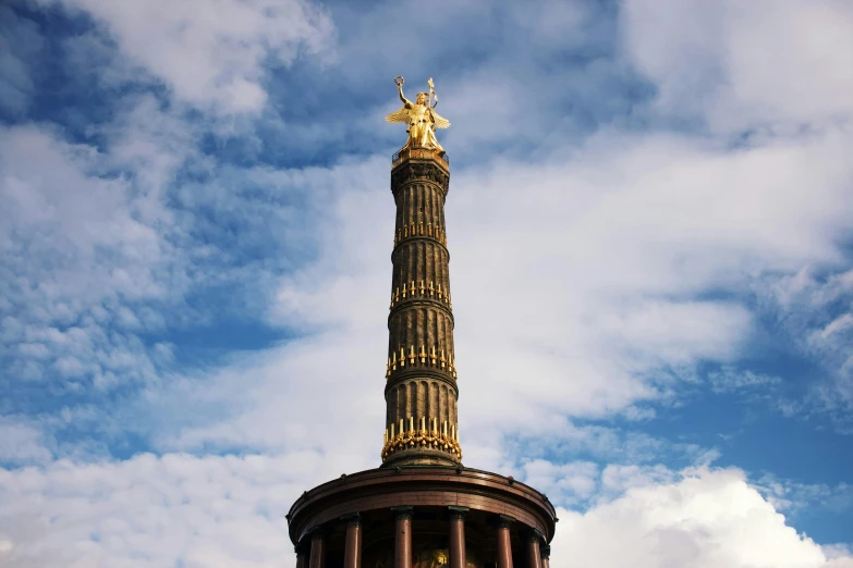 a statue is on top of a tower under a cloudy sky