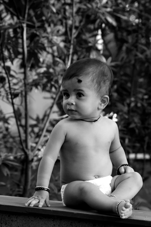 an infant sitting on top of a wooden ledge