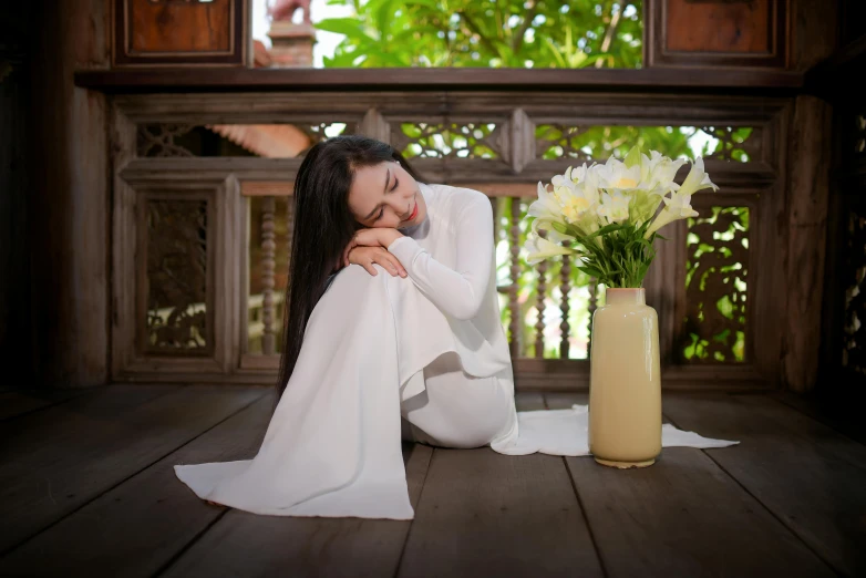a woman is sitting on the porch in white clothing