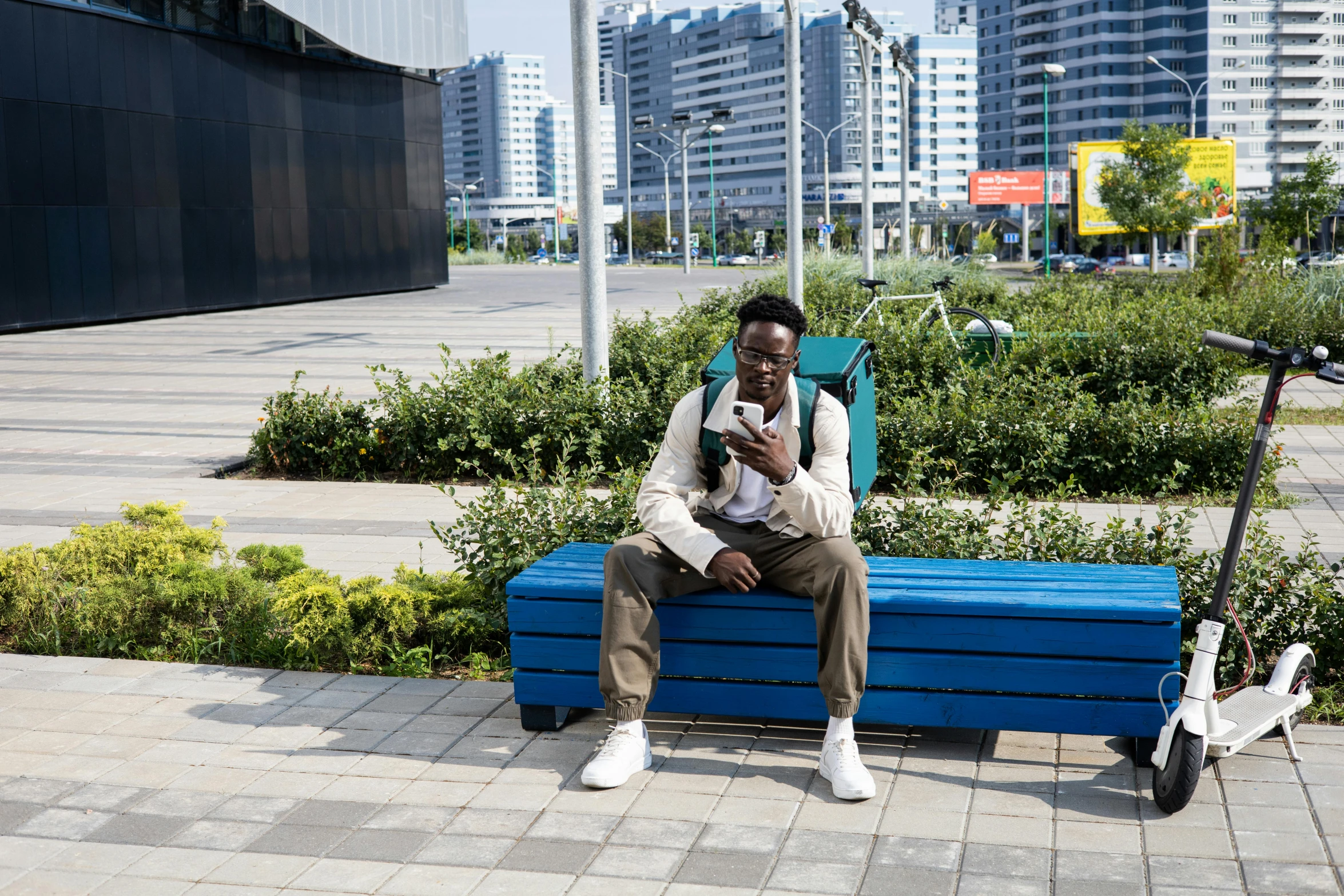 a man sitting on a blue bench near some bushes