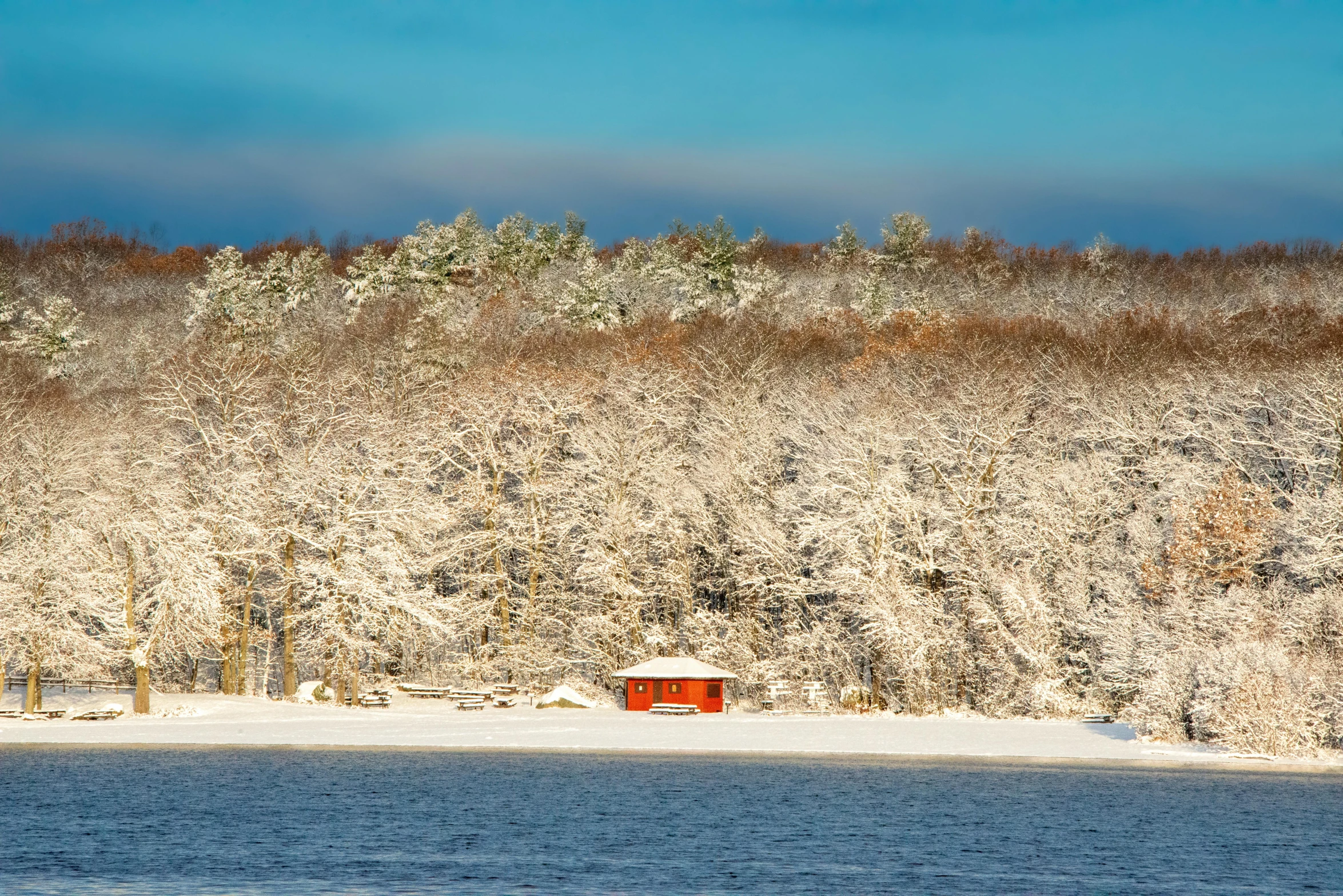 a snow covered mountain side with a small red bench in the foreground