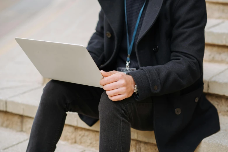 man sitting down holding a laptop computer