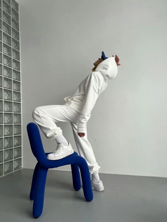 a person standing on the back of a blue and white chair