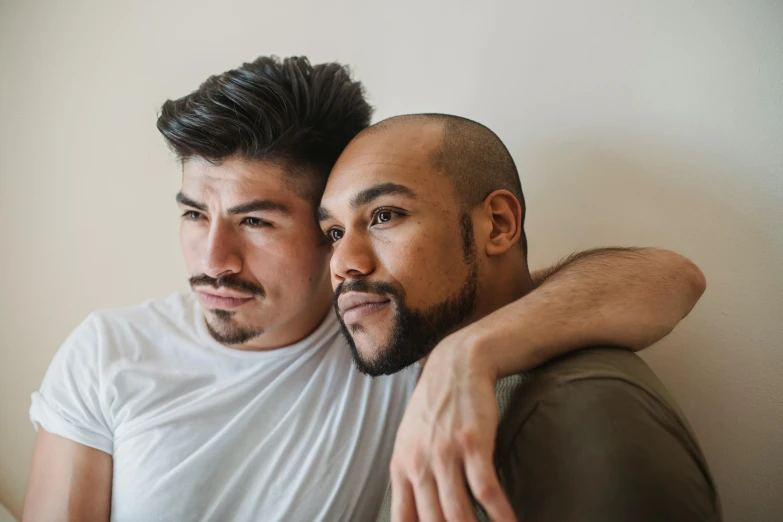 a man is hugging another man on the lap of a couch