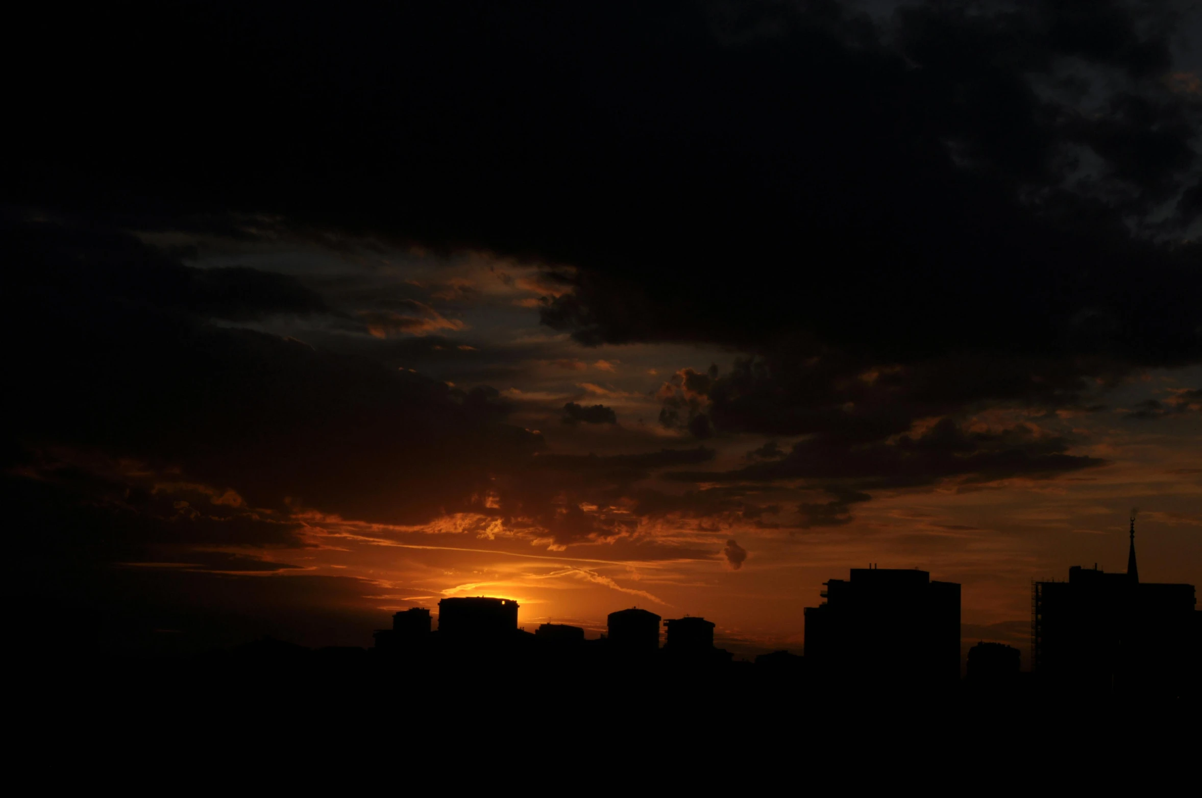 a very dark sunset over some tall buildings