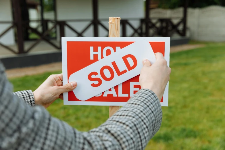 a person holding a red sign up in front of a house