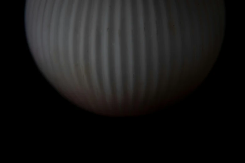 a white striped vase sitting in the dark