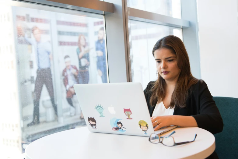 a woman using a laptop computer with cartoon stickers on the screen