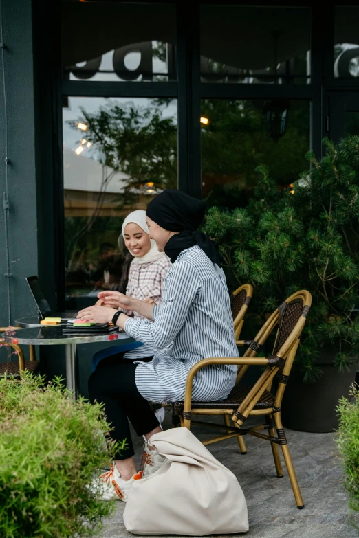 the woman is holding her small child and using her lap top