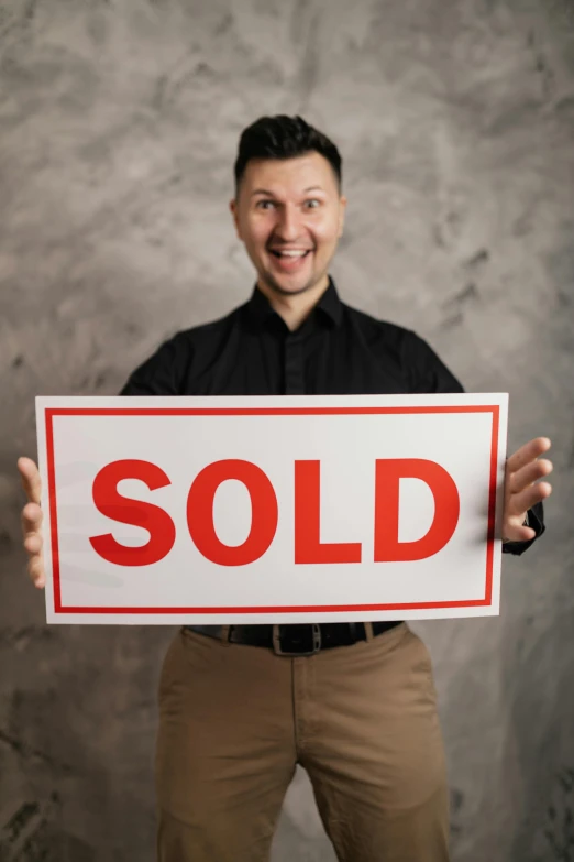 a man is holding up a sold sign