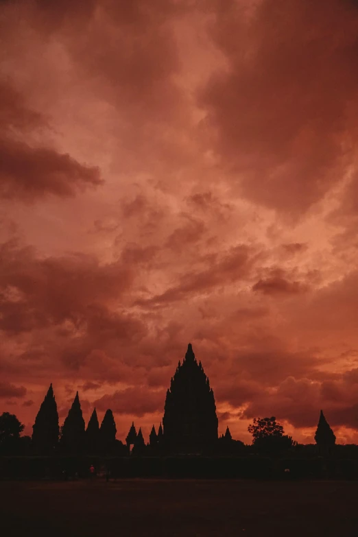 red cloudy sky with trees at sunset and large temple