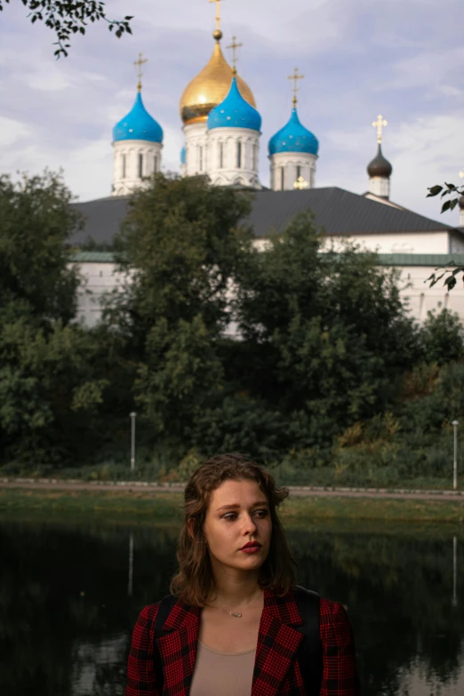 a young woman standing in front of a lake