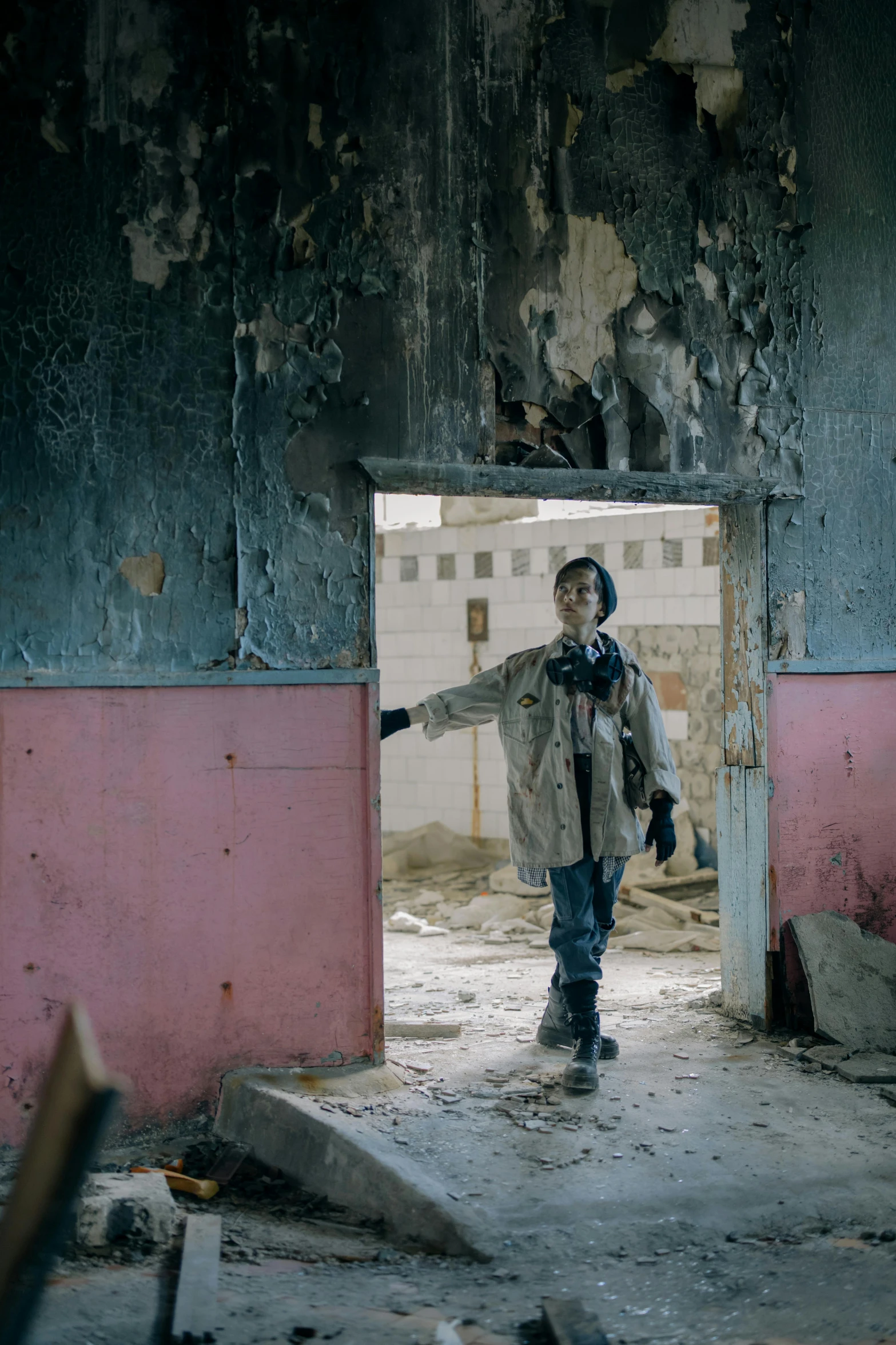 a boy in a destroyed and rundown warehouse looks at soing