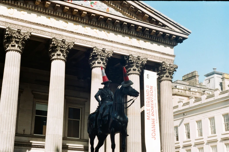 a black statue of a man on a horse in front of a building