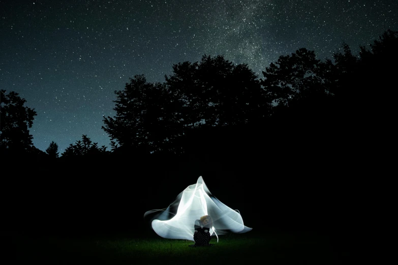 two people sit under a white fabric structure in the dark