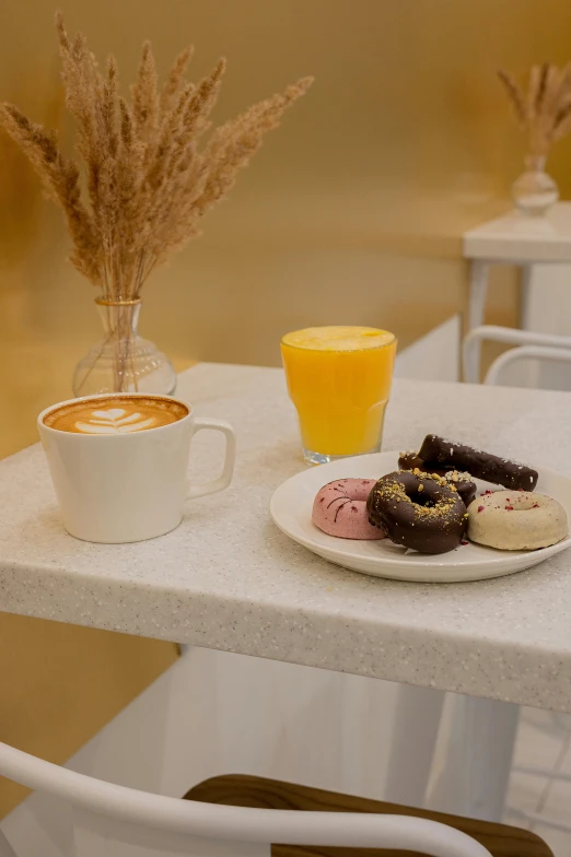 an orange glass and plate of donuts on a table