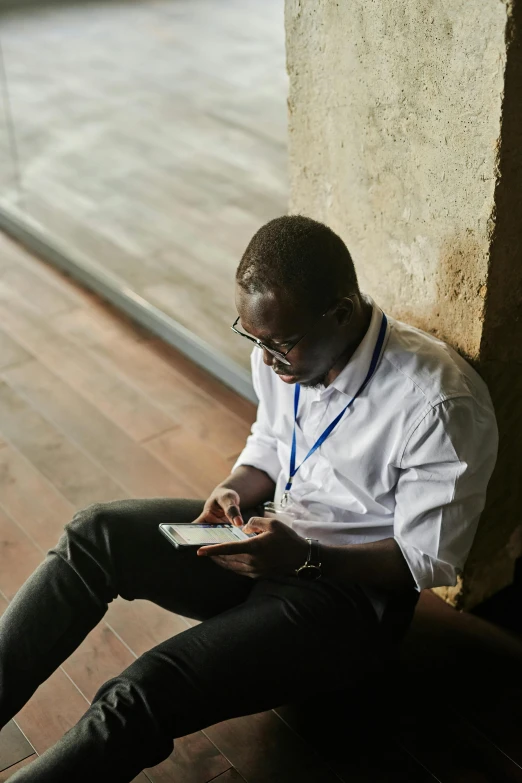 man sitting on concrete looking at his cellphone